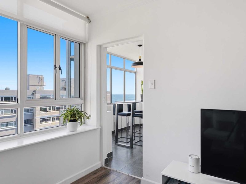 Bright living area featuring large windows with natural light, seamless transition to an enclosed balcony, and modern flooring finishes.