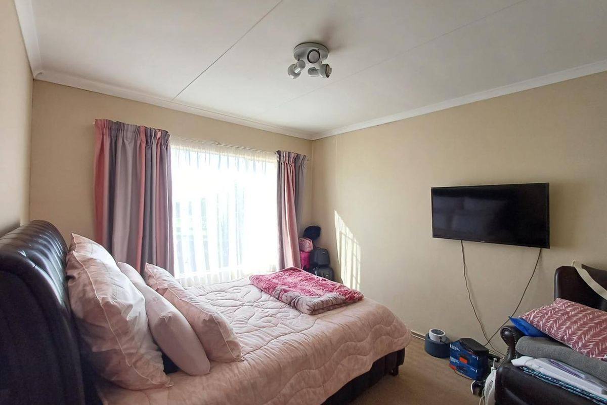A bedroom featuring neutral wall tones, a ceiling-mounted light fixture, and a window with curtain tracks.