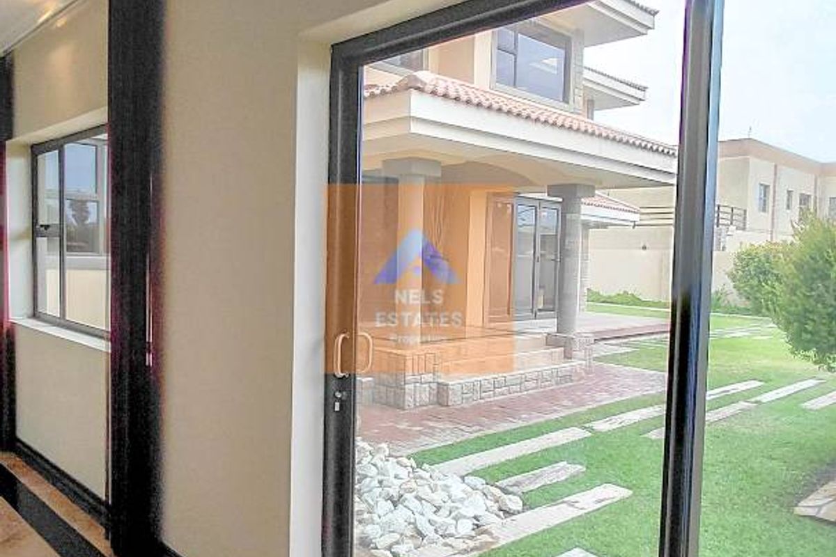 Interior view looking out through large sliding glass doors to a landscaped garden and rear patio area.