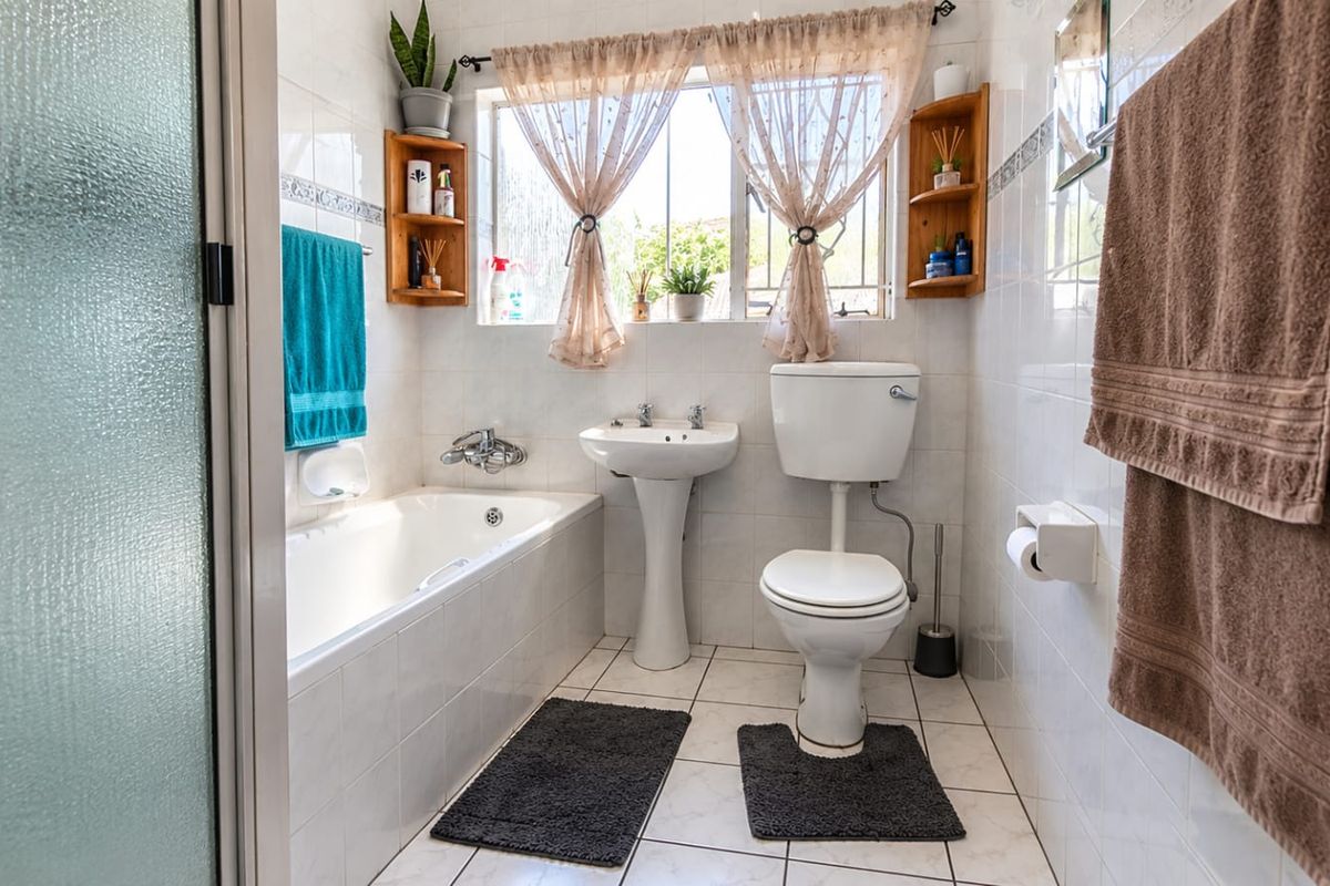 A functional bathroom featuring a bathtub, pedestal sink, and toilet, finished with classic wall and floor tiling.