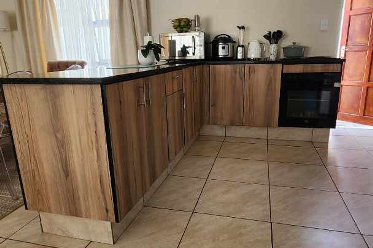 A functional kitchen featuring wood-look cabinetry, dark countertops, tiled flooring, and a built-in oven, offering a practical layout for daily meal preparation.
