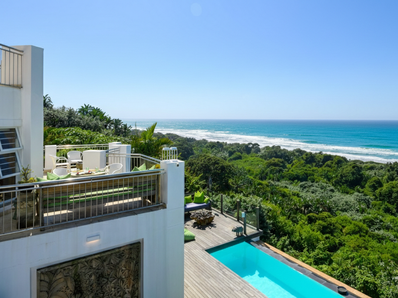 Elevated balcony and timber deck featuring a swimming pool with expansive, unobstructed ocean and coastal forest views.