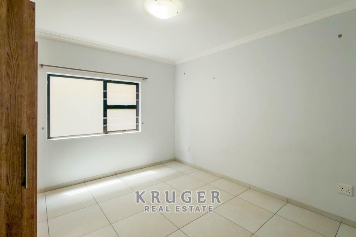 A bright, empty bedroom featuring neutral tiled flooring, a built-in cupboard, and clean white walls, ready for personalization.