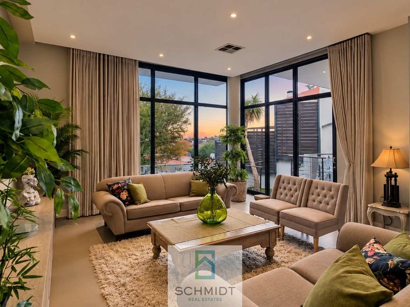 Spacious living room featuring large floor-to-ceiling windows, recessed downlighting, and a built-in fireplace, offering a bright and modern atmosphere.