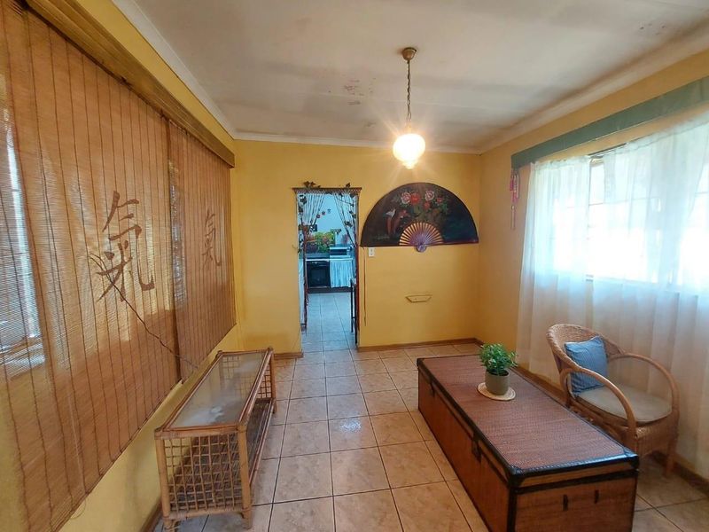 A living room featuring tiled flooring and a pendant light fixture, with visible ceiling water staining and dated wall finishes.