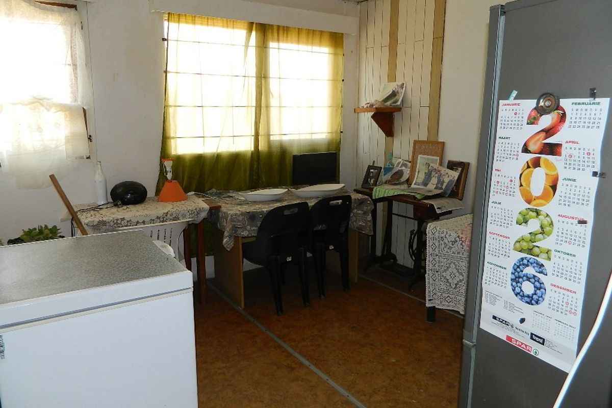 A dated kitchen area featuring vinyl flooring and vertical wood wall paneling, requiring significant cosmetic updates and modernization.
