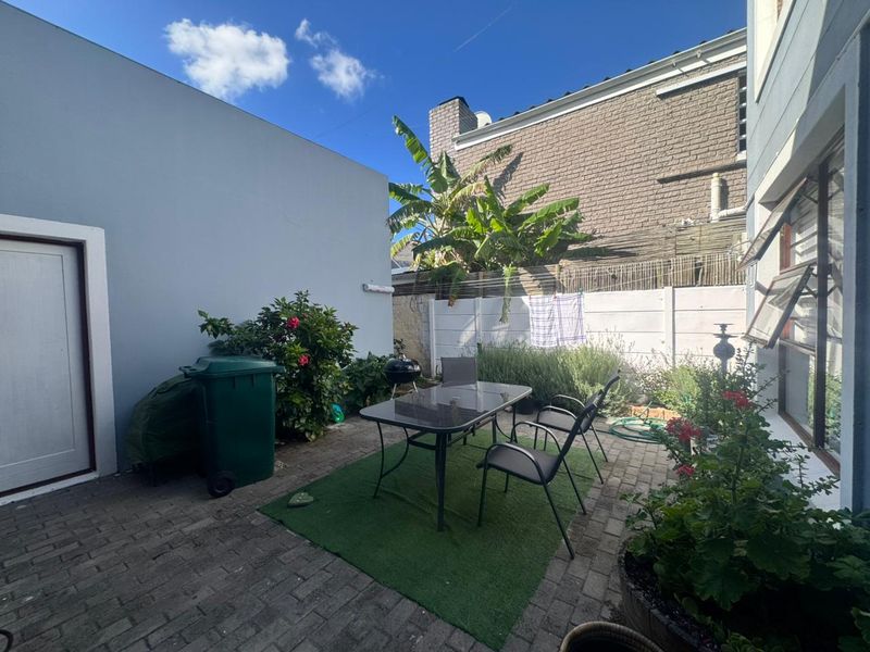 A private rear courtyard featuring paved flooring, boundary walls, and access to the main dwelling via louvre windows.
