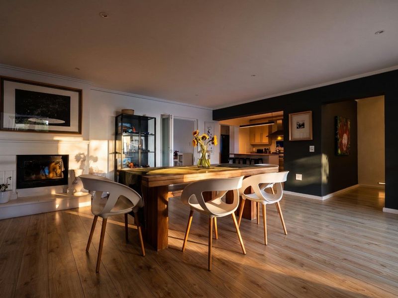 Spacious open-plan living and dining area featuring warm laminate flooring, a cozy fireplace, and a seamless transition into the adjacent kitchen space.