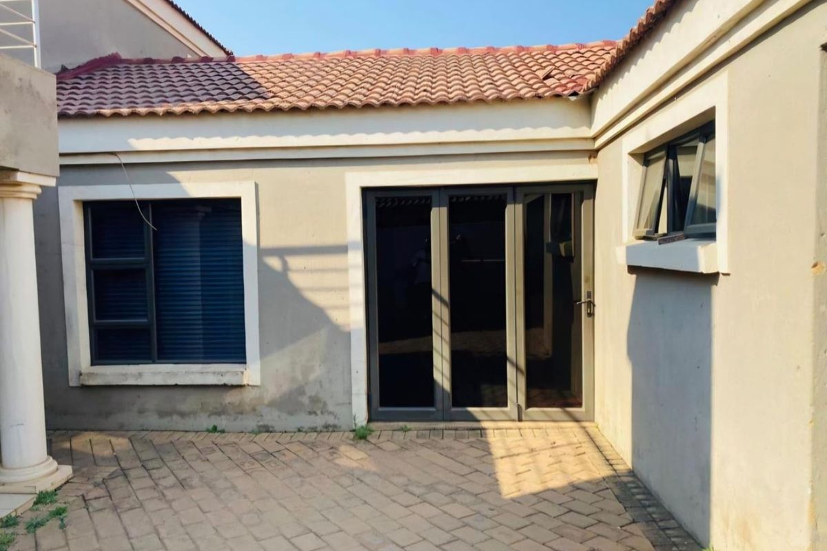 Rear exterior view of the property featuring a paved patio area, aluminium framed windows and sliding doors, and a tiled roof.