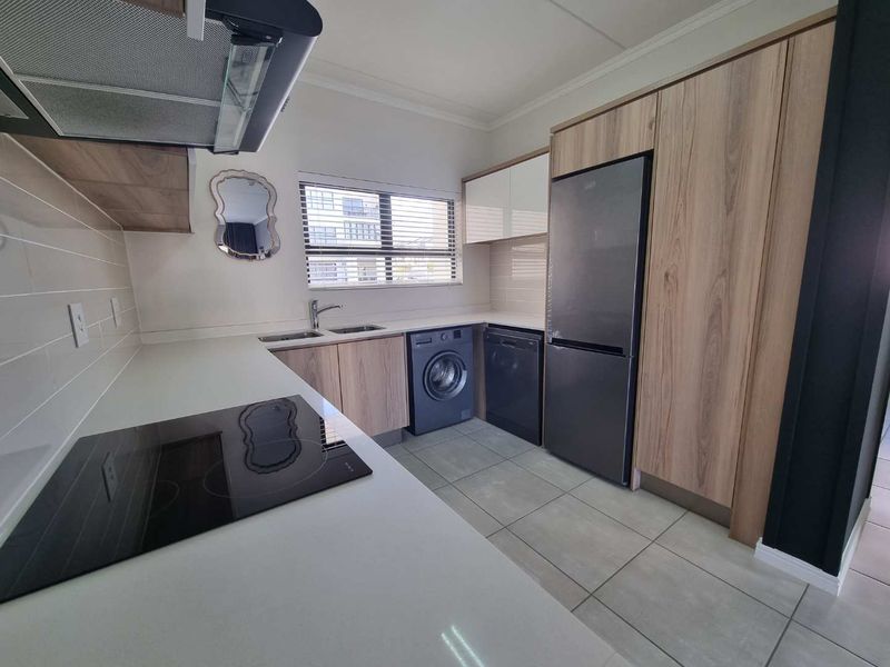 Modern kitchen featuring sleek wood-finish cabinetry, stone countertops, integrated appliances, and a tiled backsplash with a clean, contemporary aesthetic.