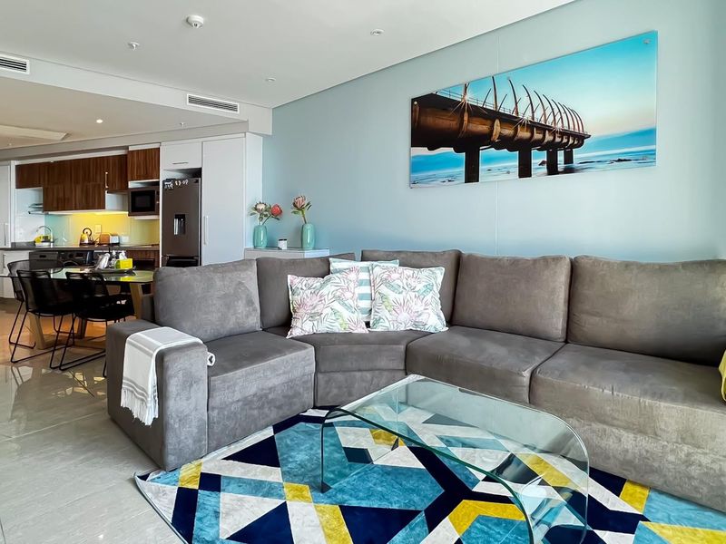 Modern open-plan living area featuring tiled flooring, recessed downlights, ducted air conditioning, and a well-appointed kitchen with integrated appliances.