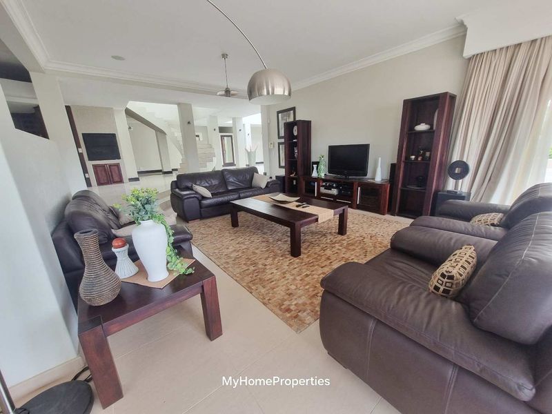 Spacious living room featuring neutral tiled flooring, recessed ceiling lighting, and an open-plan layout leading to a staircase.