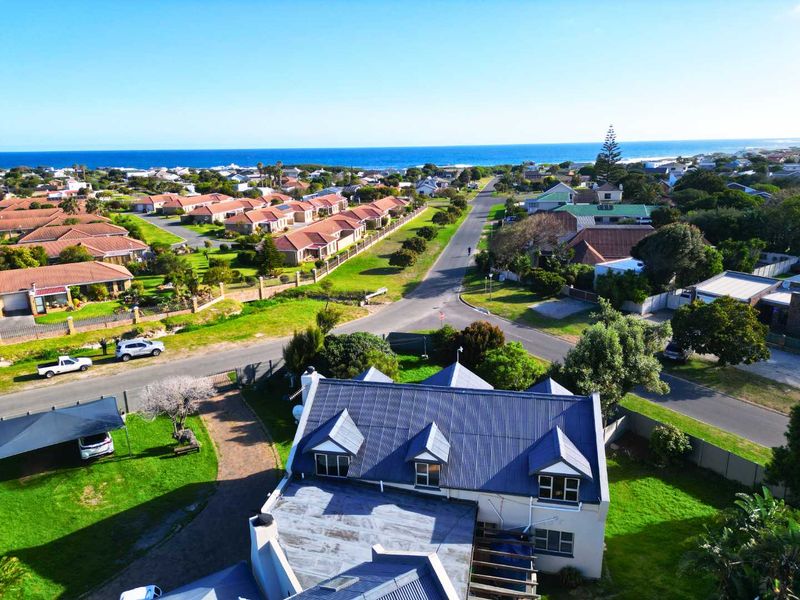 Aerial view of the property showing the roof structure, driveway, and surrounding coastal neighborhood landscape.
