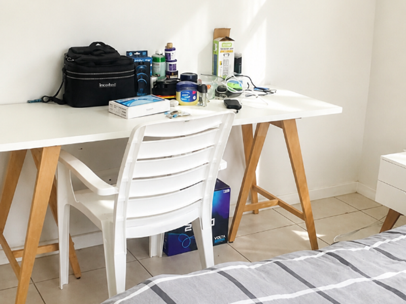 A bedroom featuring neutral walls and tiled flooring, providing a functional space for rest or study.