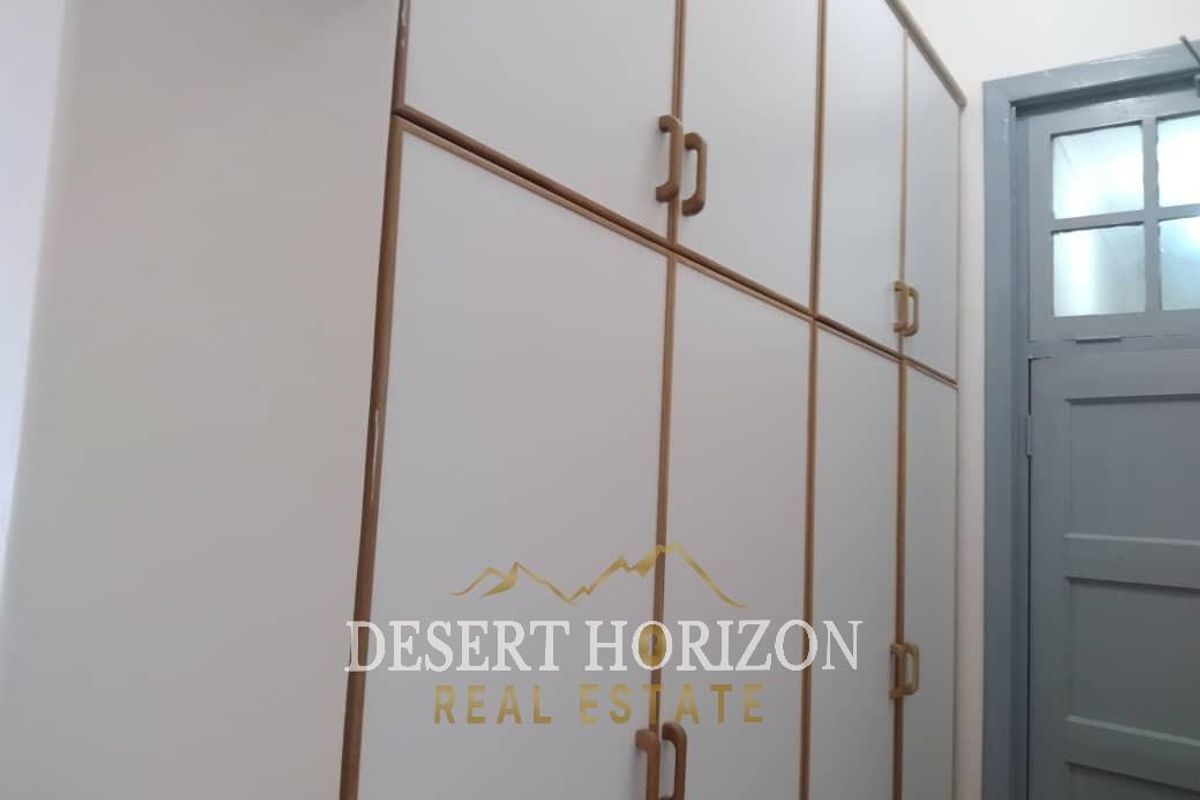A bedroom featuring built-in white cabinetry with wooden trim and a classic panel door.