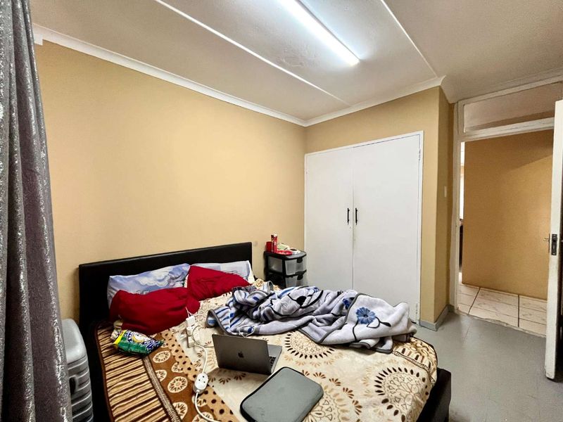 A bedroom featuring a built-in wardrobe and basic finishes, requiring some cosmetic updates to the ceiling and walls to improve its overall appeal.