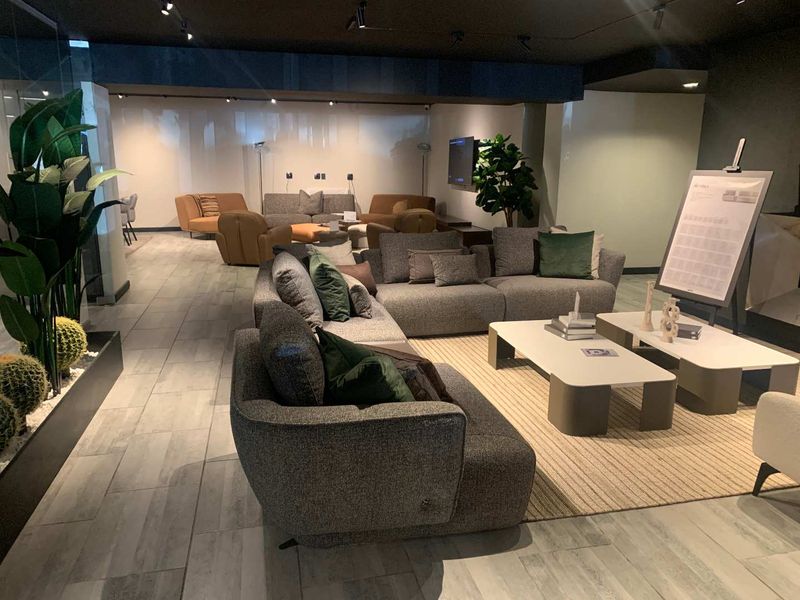 A modern, well-lit retail showroom space featuring contemporary tiled flooring and professional track lighting, suitable for high-end furniture display.