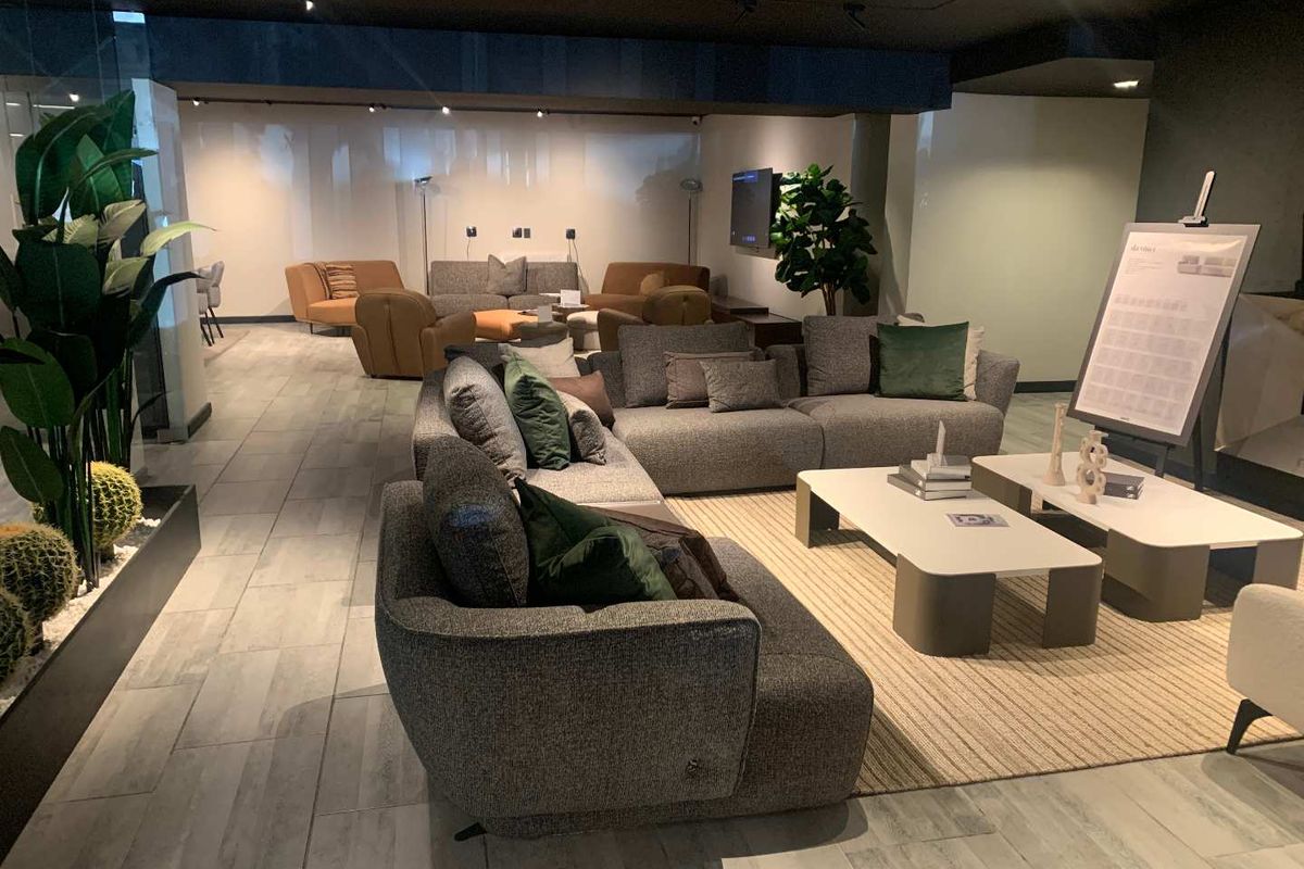 A modern, well-lit retail showroom space featuring contemporary tiled flooring and professional track lighting, suitable for high-end furniture display.