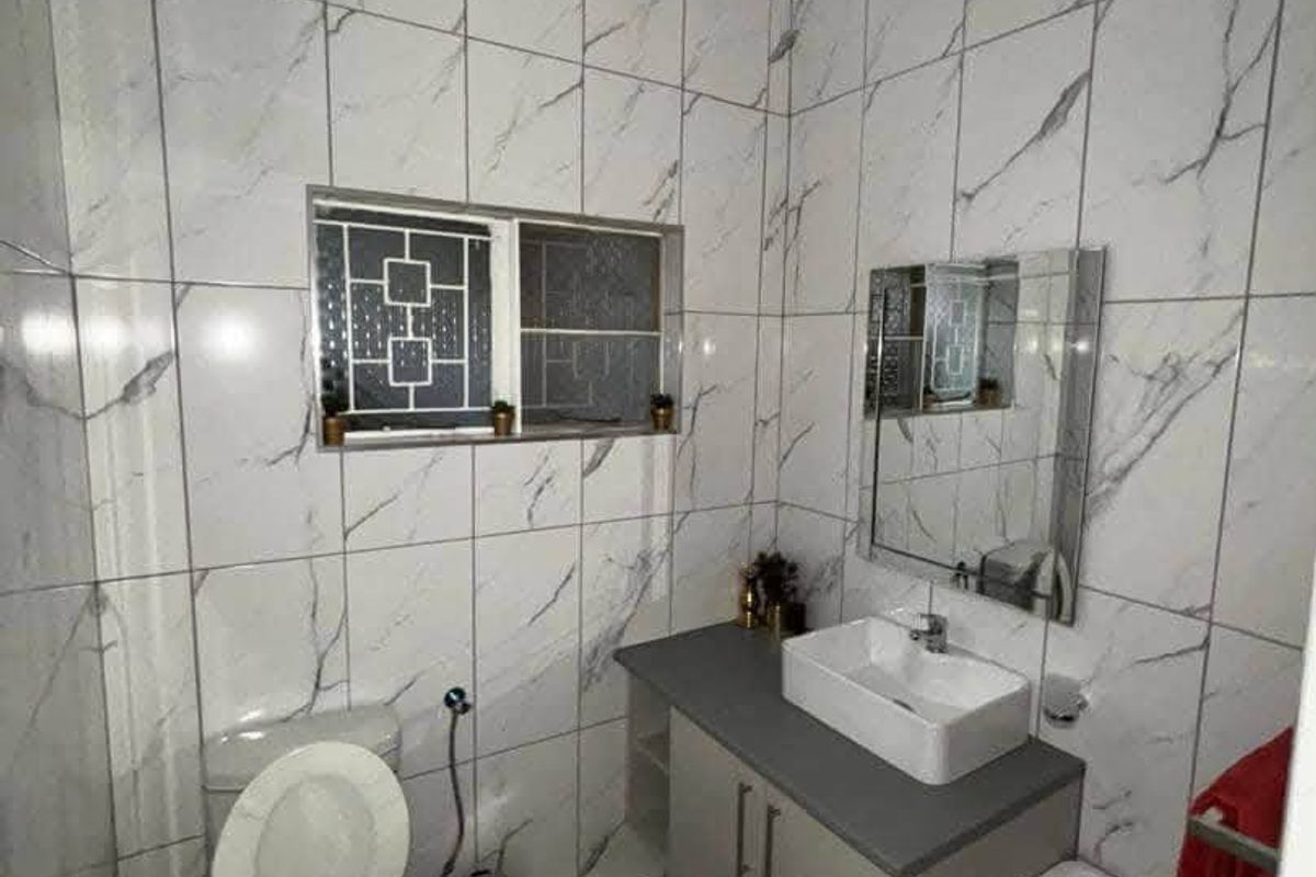 A modern bathroom featuring marble-look wall tiles, a vanity cabinet with a countertop basin, and a wall-mounted mirror.