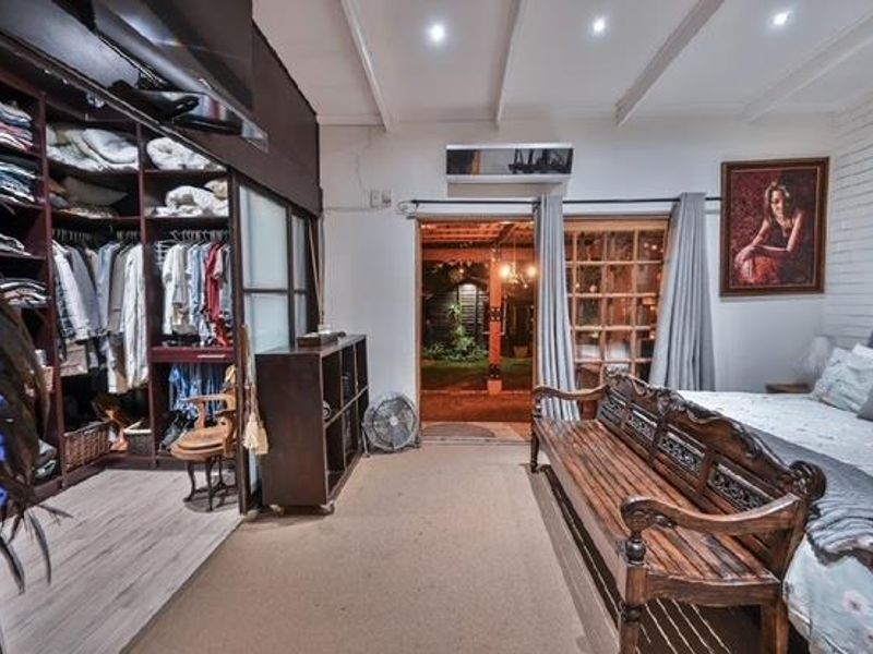 Spacious bedroom featuring built-in wardrobe storage, recessed lighting, air conditioning, and direct access to an outdoor patio area.