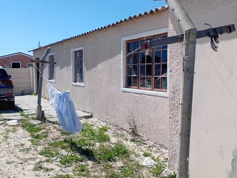 Rear exterior view of the property featuring plastered walls, steel-framed windows, and a yard area with concrete washing line poles.