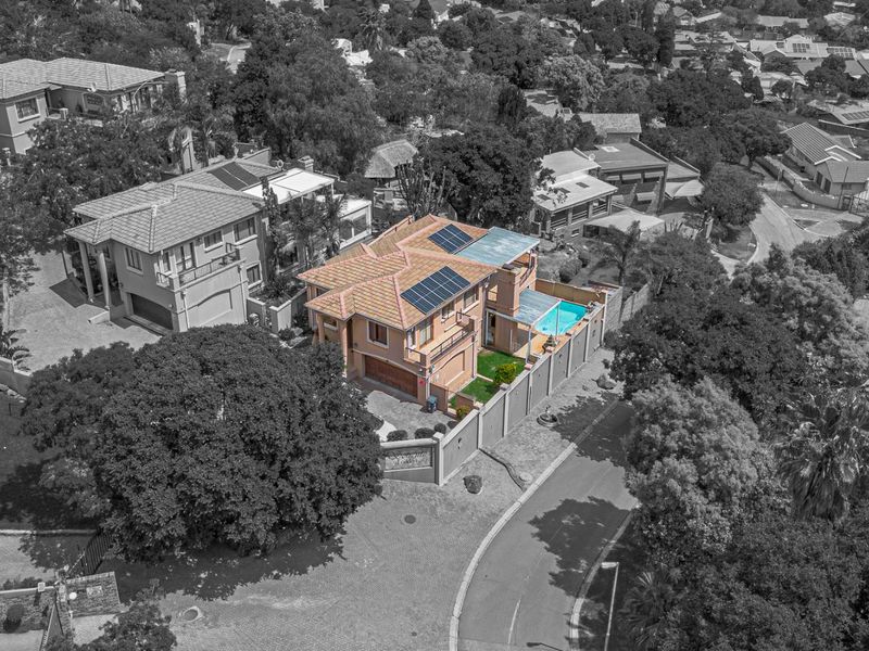 Aerial view of a residential property featuring a tiled roof with solar panels, a private swimming pool, and a secure perimeter wall.