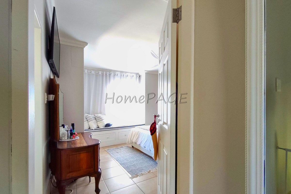 A view into a bedroom featuring a built-in window seat with storage cabinetry and tiled flooring.