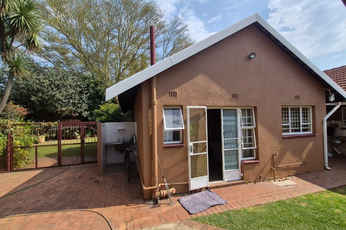 Rear exterior view of the property featuring brick paving, an external sink area, and security features on windows and doors.