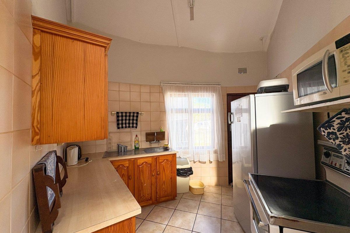 A functional kitchen featuring wooden cabinetry, tiled backsplash, and tiled flooring, offering a dated aesthetic with potential for modernization.