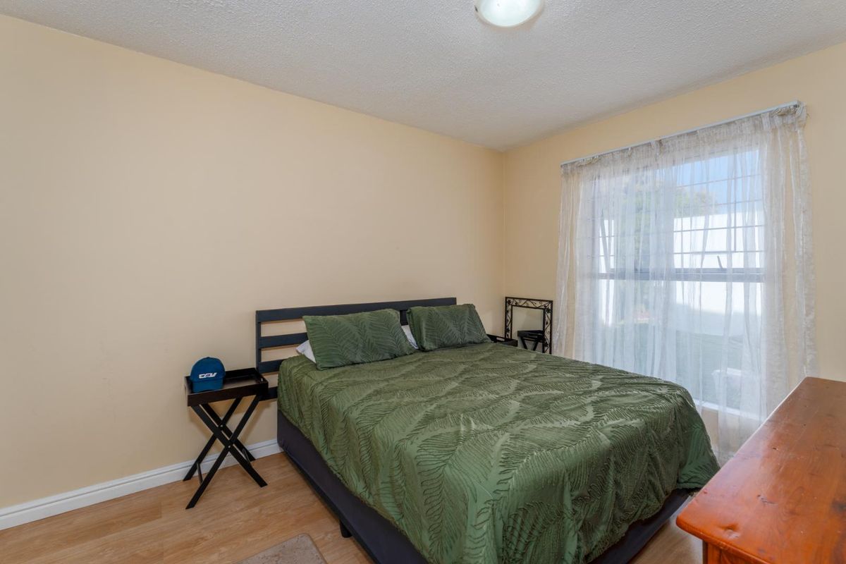 A standard bedroom featuring laminate flooring, textured ceilings, and a window with natural light.