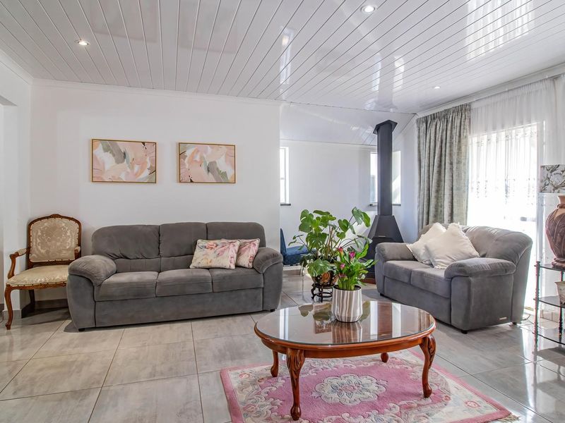 A bright living room featuring large format floor tiles, a tongue and groove ceiling with recessed lighting, and a modern freestanding fireplace.