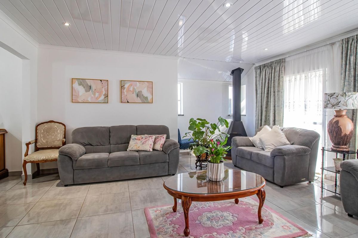 A bright living room featuring large format floor tiles, a tongue and groove ceiling with recessed lighting, and a modern freestanding fireplace.