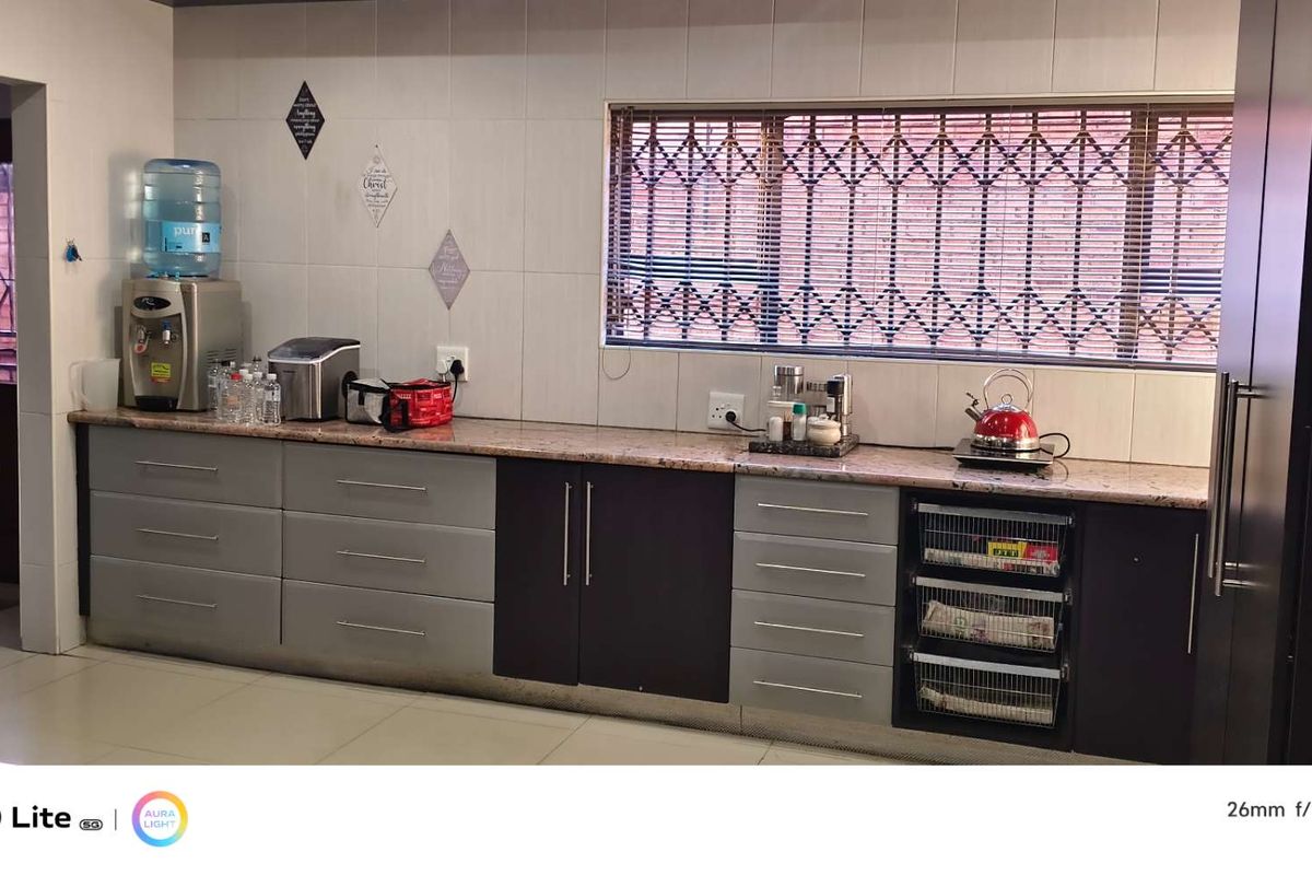 A functional kitchen featuring granite countertops, two-tone cabinetry, and a window with security bars, providing a practical workspace for daily meal preparation.