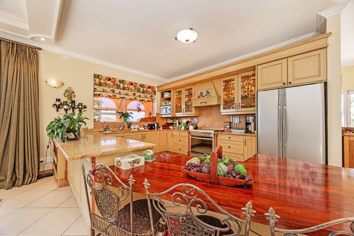 A spacious kitchen featuring granite countertops, extensive built-in cabinetry, a built-in oven, and tiled flooring, offering a functional and traditional layout.
