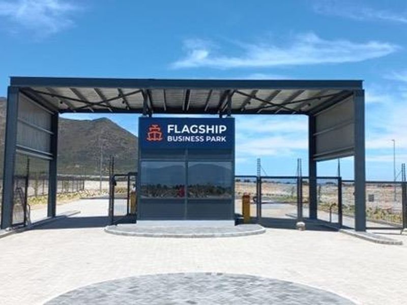Modern security gatehouse entrance for Flagship Business Park, featuring a steel structure, paved driveway, and perimeter fencing.