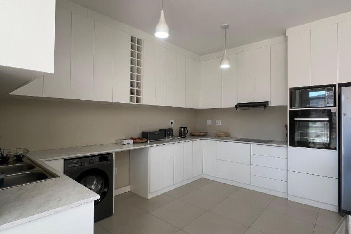 Modern kitchen featuring white cabinetry, stone countertops, integrated appliances, and tiled flooring, offering a clean and functional workspace.