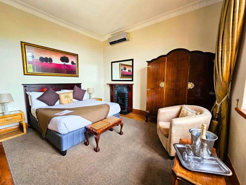 A well-maintained bedroom featuring a classic fireplace with tiled surround, wall-mounted air conditioning, and traditional coving details.