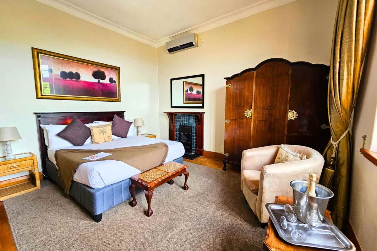 A well-maintained bedroom featuring a classic fireplace with tiled surround, wall-mounted air conditioning, and traditional coving details.