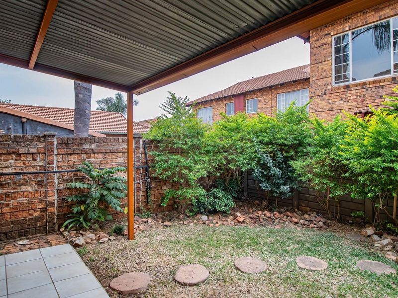 A covered patio area overlooking a small private garden with brick boundary walls and established greenery.