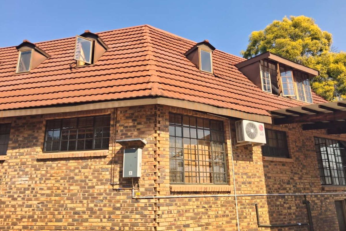 Exterior view of a face brick farm-style dwelling featuring a tiled roof, dormer windows, and an installed air conditioning unit.