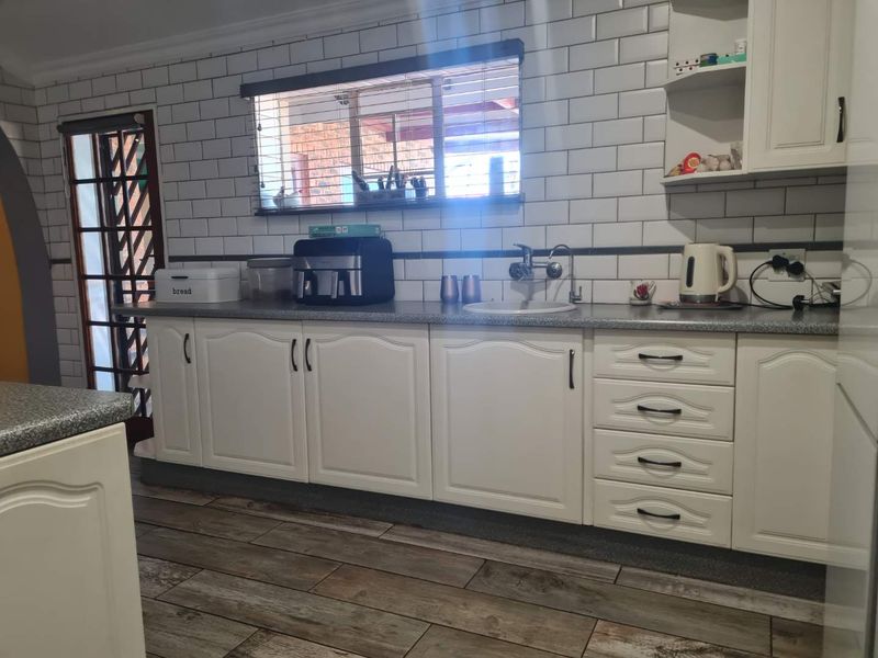 A functional kitchen featuring white cabinetry, subway tile backsplash, laminate countertops, and wood-look tile flooring.