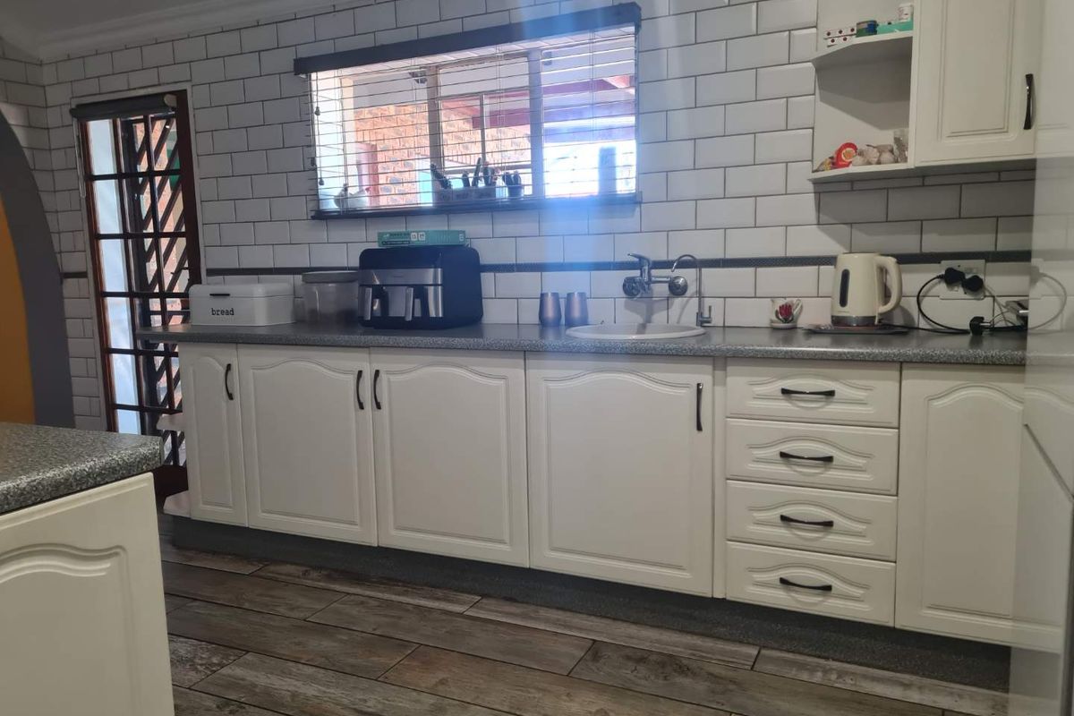 A functional kitchen featuring white cabinetry, subway tile backsplash, laminate countertops, and wood-look tile flooring.