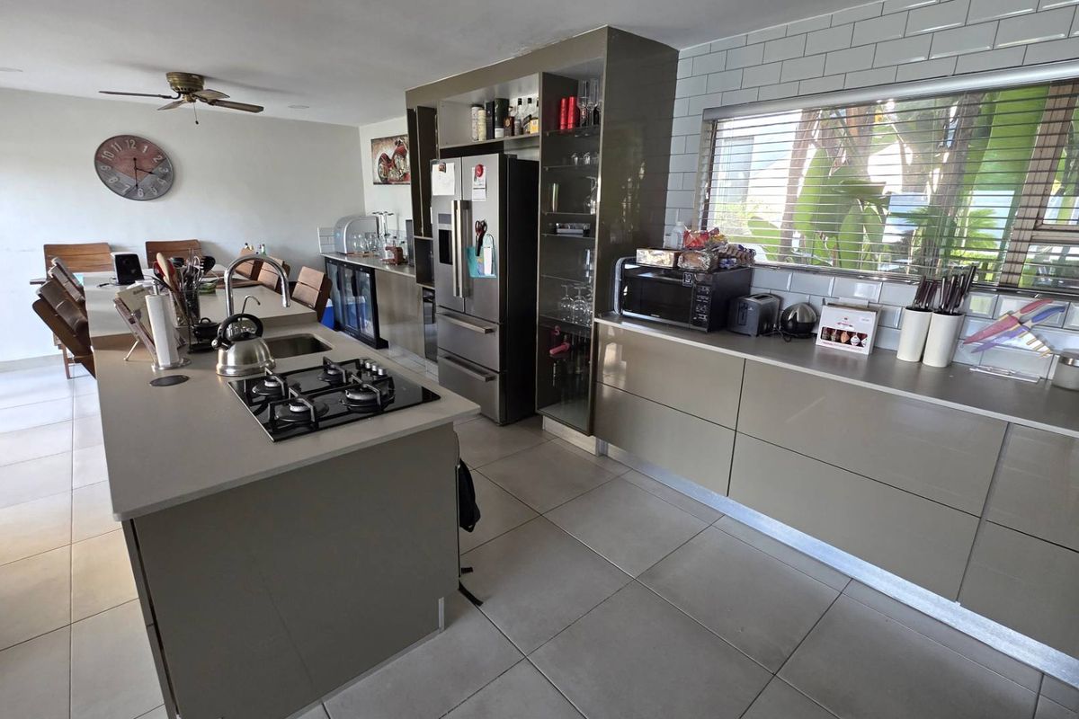 Modern kitchen featuring a central island with gas cooktop, sleek cabinetry, subway tile backsplash, and integrated storage solutions.