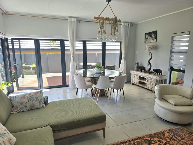 Spacious open-plan living and dining area featuring large aluminium stacker doors that provide seamless access to the outdoor patio and garden.