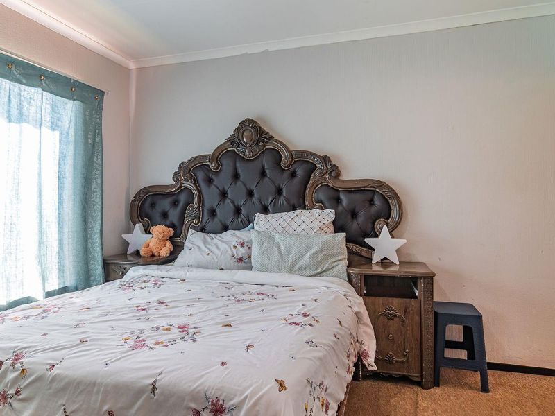 A standard bedroom featuring carpeted flooring and coved ceiling detailing, providing a functional space for rest.