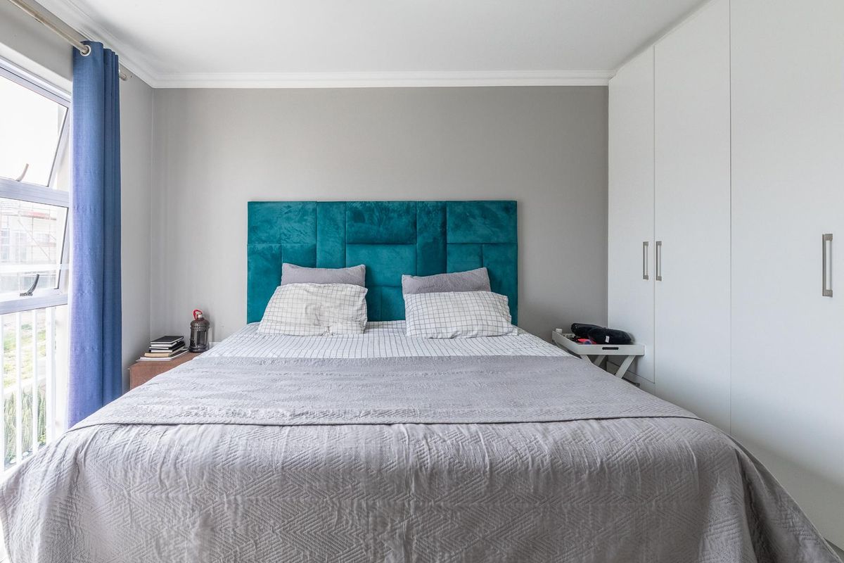 A well-maintained bedroom featuring built-in floor-to-ceiling wardrobes and a large window providing natural light.