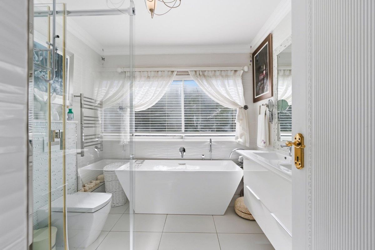 Modern, well-appointed bathroom featuring a sleek freestanding bathtub, glass-enclosed shower, wall-hung vanity, and contemporary fixtures with a bright, clean aesthetic.