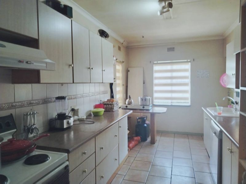 A functional kitchen featuring built-in cabinetry, laminate countertops, tiled backsplash, and ceramic flooring, offering a practical layout with ample storage space.