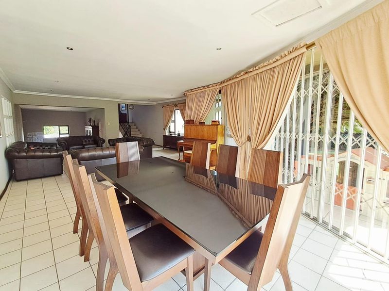 Spacious open-plan living and dining area featuring tiled flooring, recessed lighting, and direct access to the outdoor area through a secure sliding gate.