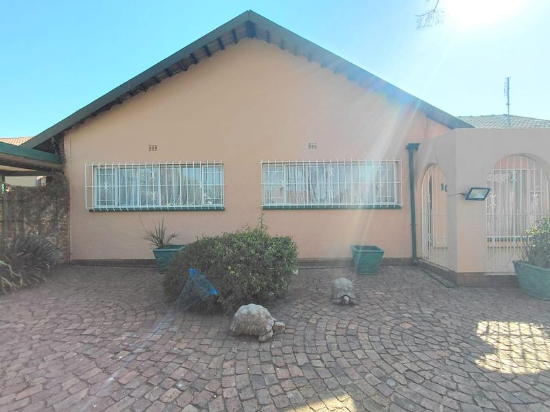 Front facade of the house featuring a paved driveway, security bars on windows, and an arched entrance area.
